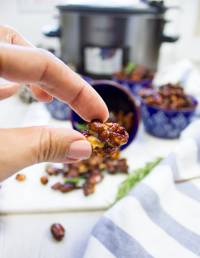 A hand holding a spiced walnut piece showing the crunch