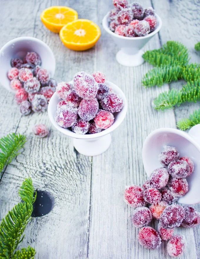 three bowls of sugared cranberries with clementines