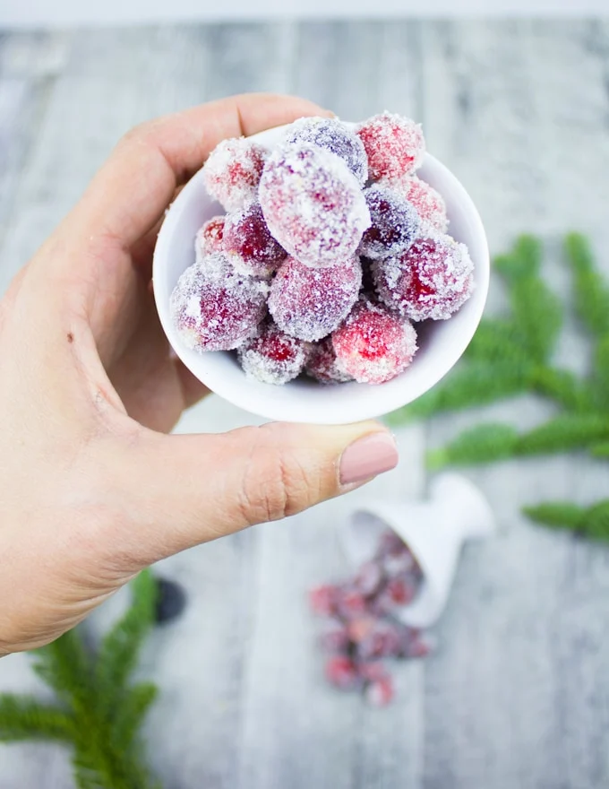 A hand holding a bowl of cranberries