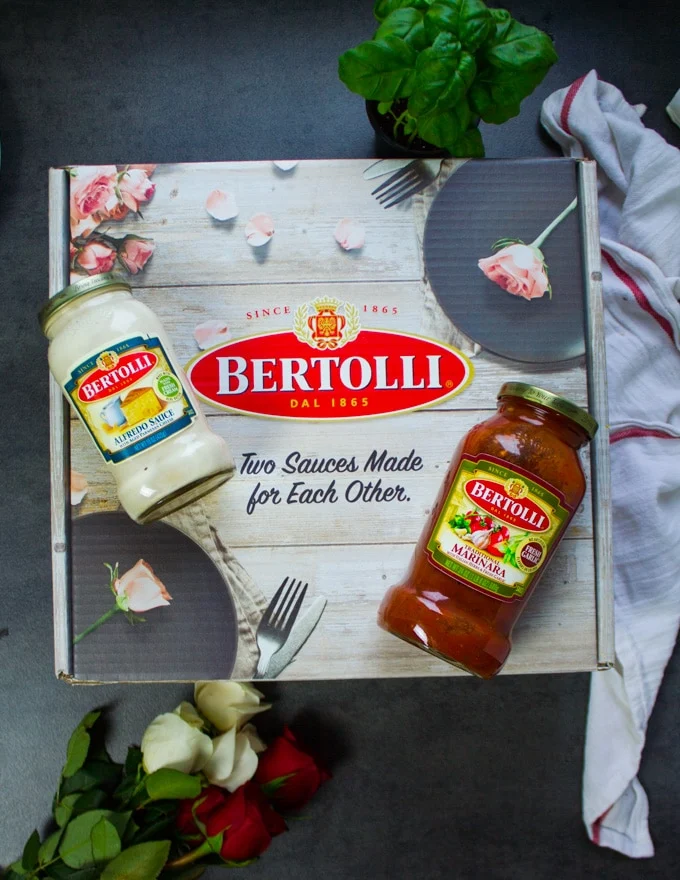 A box of Bertollli with two jars of sauces on top of it