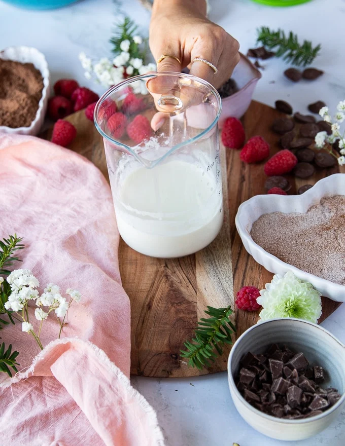 A hand holding a jar of hot heavy cream