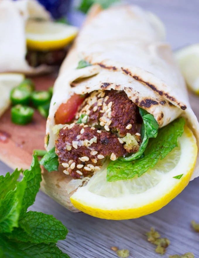 A finished falafel wrap close up showing the flafel, fresh mint and lemon slices.
