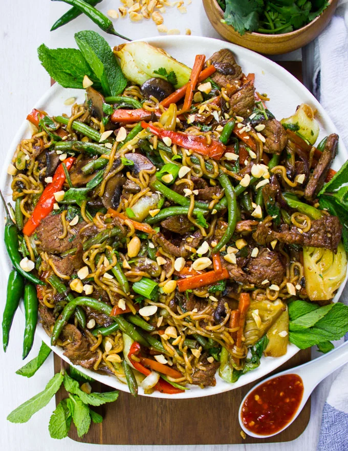 A plate of stir fry recipe on a white plate garnished with peanuts and mint