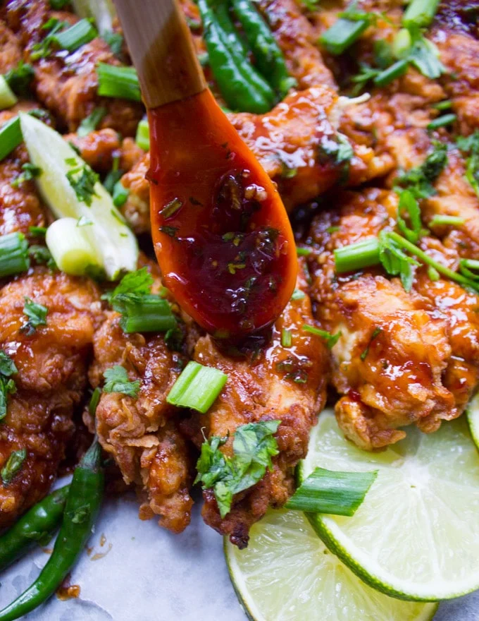 A spoon drizzling the Korean Fried Chicken Sauce over the fried chicken