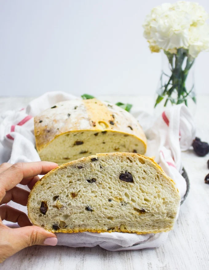 A hand holding a slice of bread close up with the load at the back