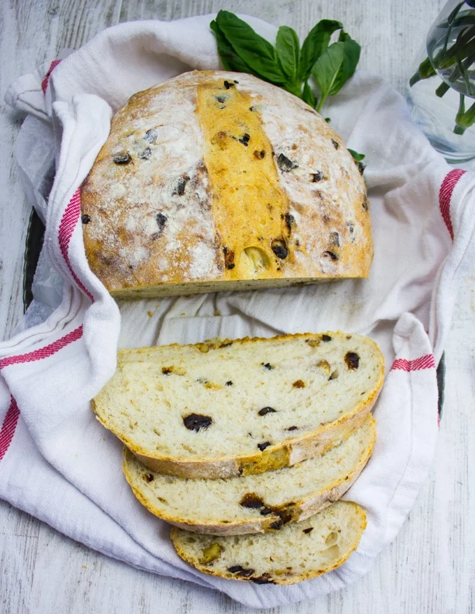 A whole loaf of bread sliced up on a kitchen towel