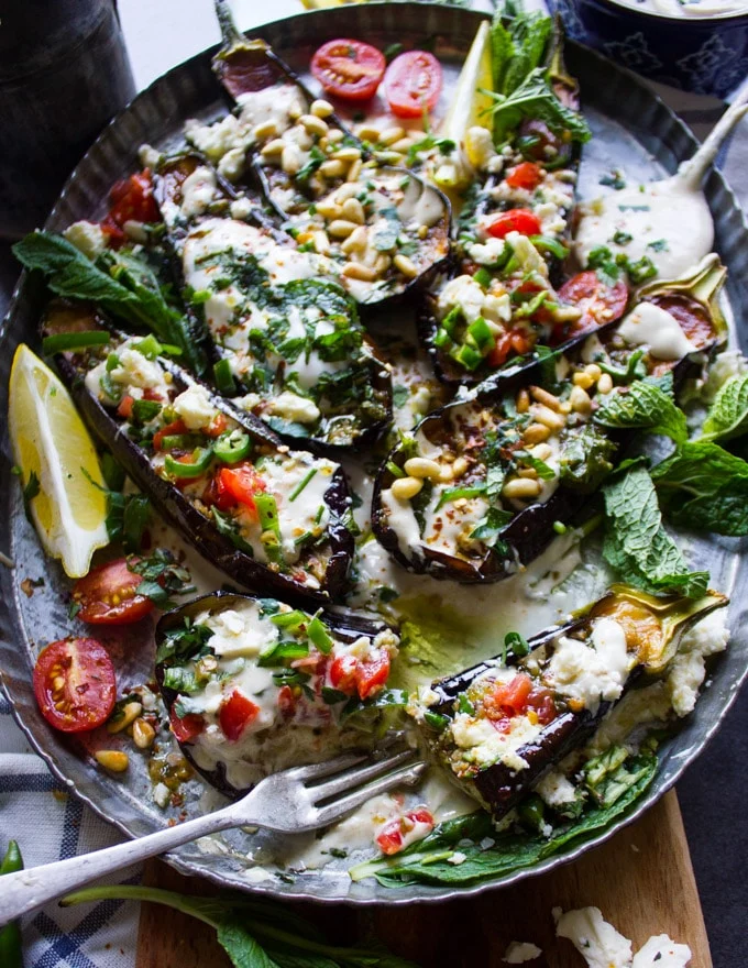 Fried eggplant salad over tahini sauce and a fork on the plate for serving and eating