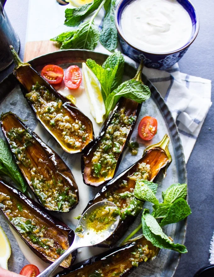 A spoon drizzling the magic sauce of olive oil vinegar and garlic over the fried eggplants right off the oil