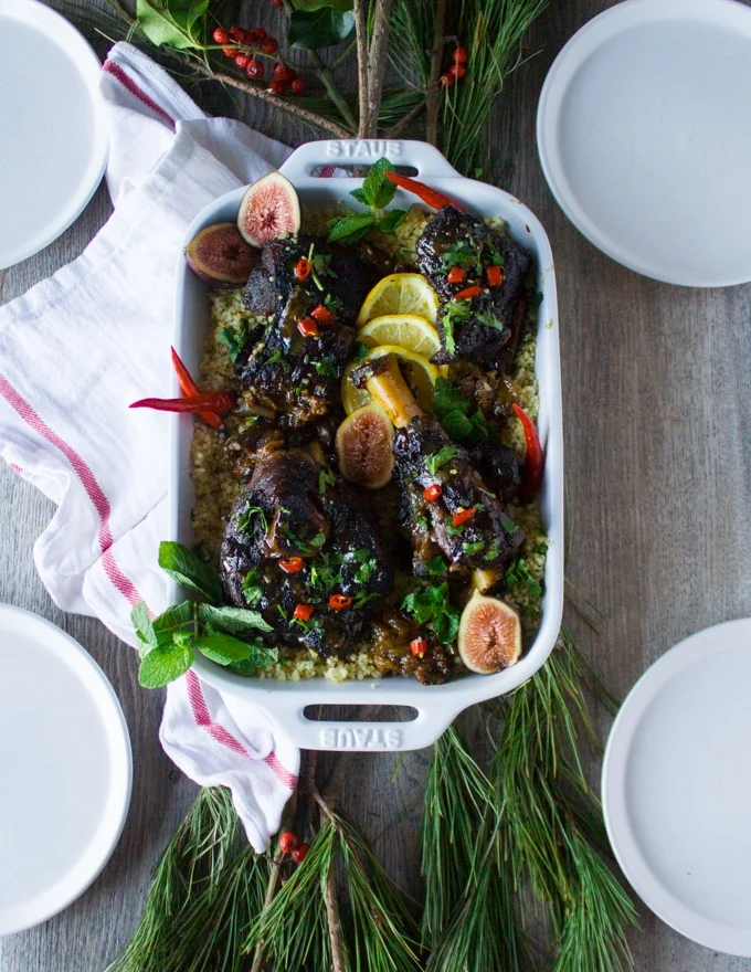 The cooked lamb meat over couscous in a serving plate surrounded by a tea towel