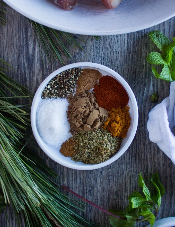 A plate with a collection of Moroccan Spices including: turmeric, nutmeg, allspice, paprika, salt pepper, oregano, cinnamon