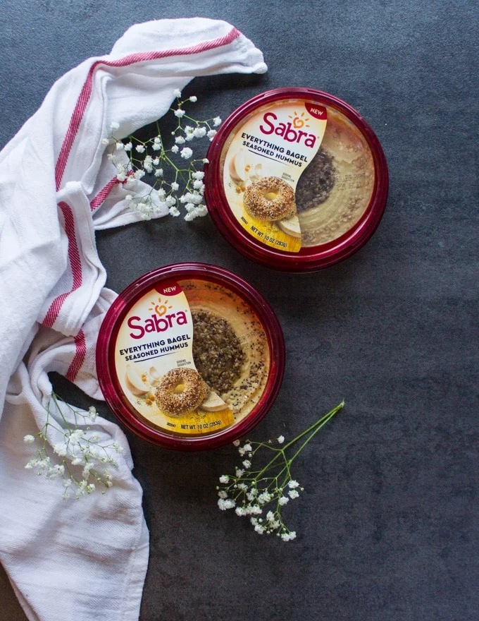 two tibs of Sabra hummus on a table with a tea towel around them