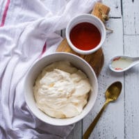 Ingredients for the spicy mayo recipe including a bowl of mayonnaise, a bowl of Sriracha hot sauce and a teaspoon of rice vinegar