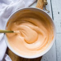 A bowl of spicy mayo recipe and a spoon swirled in to show the texture and creamy sauce