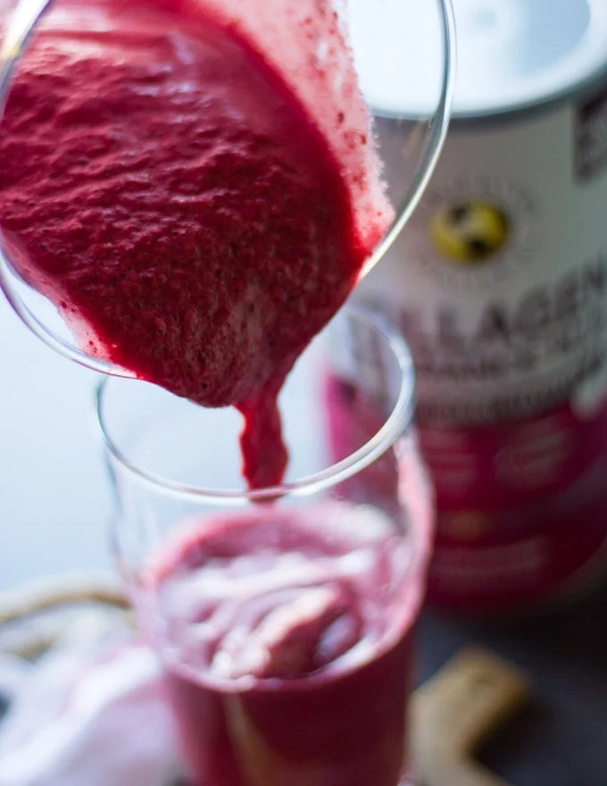 a jar pouring the cherry smoothie layer at the bottom of the smoothie cup