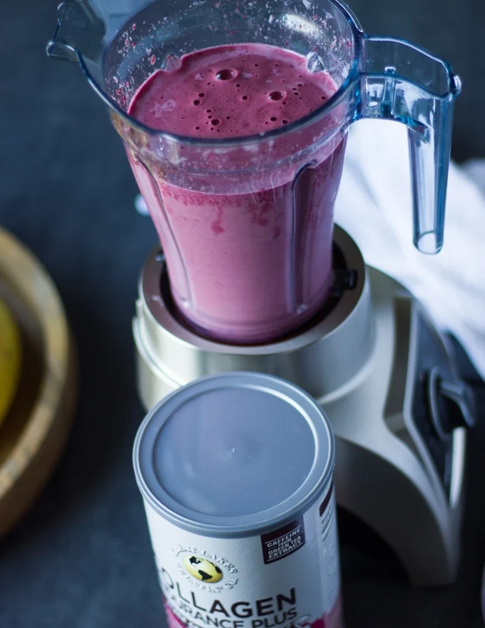 A blender with the cherry smoothie layer finished and thick
