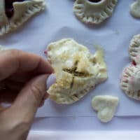 A hand sprinkling coarse sugar over the tops of the pie crust before baking