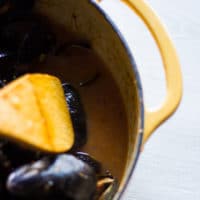 A spoon showing off the sauce at the pan after mussels have cooked