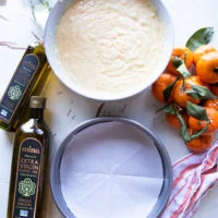 The cake ingredients all mixed in a bowl and a 9 inch cake pan is lined with parchment paper ready for the batter