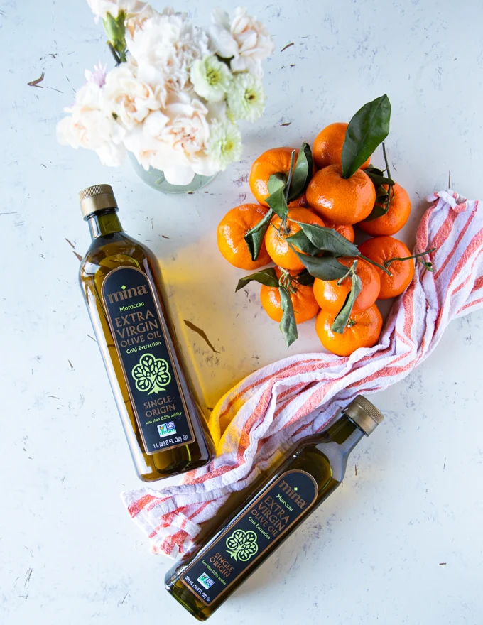 two bottles of Moroccan olive oil surrounded by clementine oranges and a tea towel