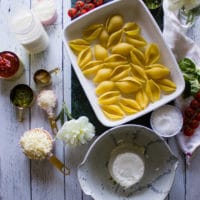 Ingredients for ricotta stuffed shells including pasta, ricotta, parmesan, mozzarella, spices, tomatoes, salt.