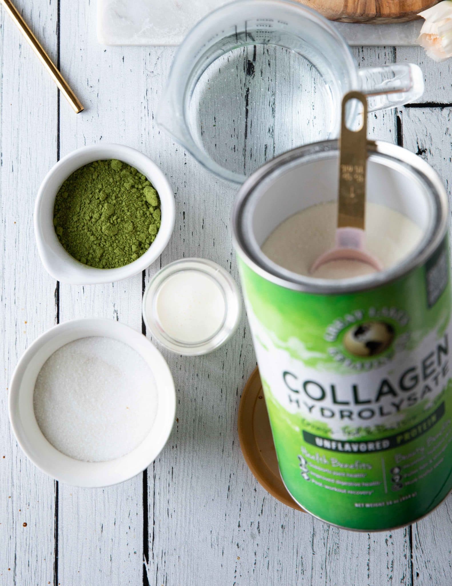 Ingredients for matcha dalgona with matcha powder, sugar, cream, collagen and an electric mixer