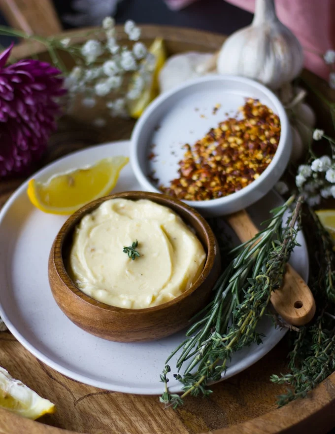 garlic butter sauce for steak surpunded by a bowl of chilli flakes and some fresh rosemary