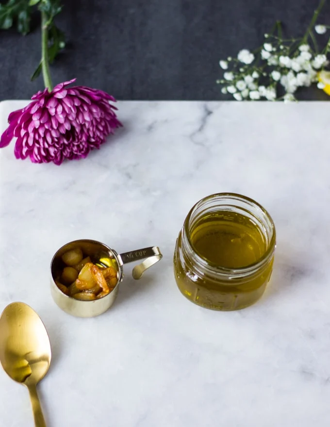 Strained olive oil in a jar and the cooked garlic separately ready to make the sauce