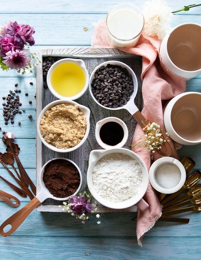 Ingredients in a tray for the brownie in a mug recipe including, cocoa powder, flour, brown sugar, oil, chocolate chips. vanilla, milk and oil
