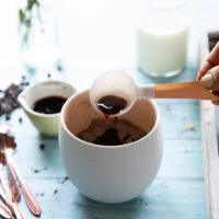 A hand adding the vanilla to the mug