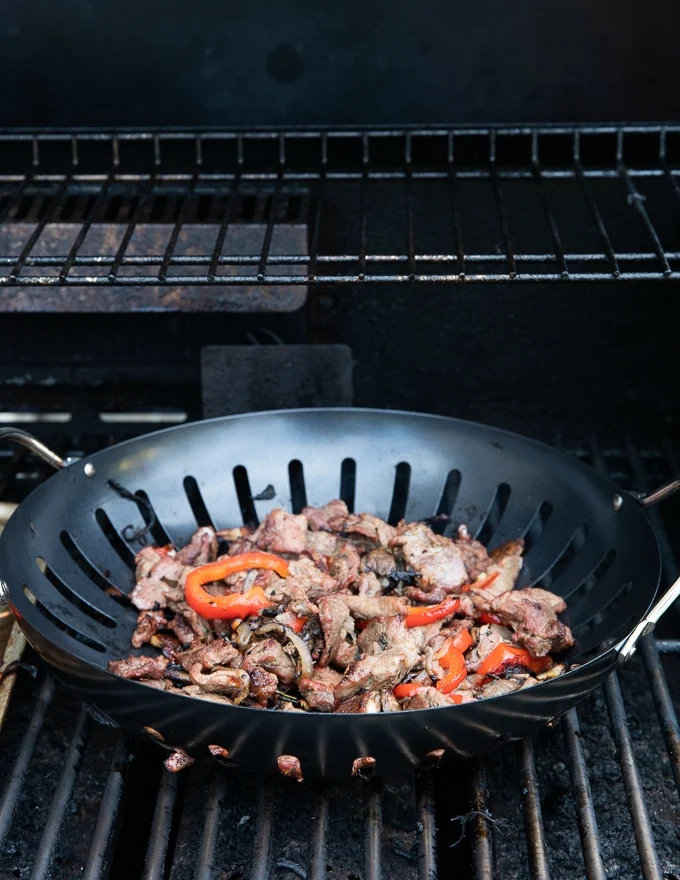 showing option for the BBQ using a perforated grill pan with the meat and veggies mixture in the pan over the grill for the philly cheesesteak sliders