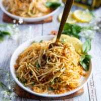 A fork swirling the spaghetti with olive oil sauce in a bowl