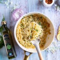 cooked spaghetti being added to the olive oil skillet once the garlic and olive oil sauce is ready