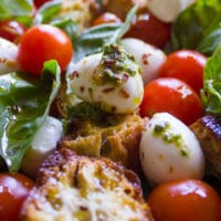 close up of one mozzarella and tomato bite of the caprese salad all dressed up with basil and some extra chilli flakes