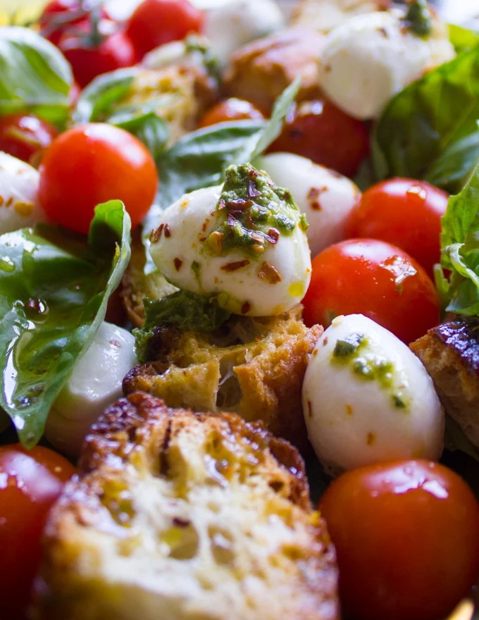 close up of one mozzarella and tomato bite of the caprese salad all dressed up with basil and some extra chilli flakes