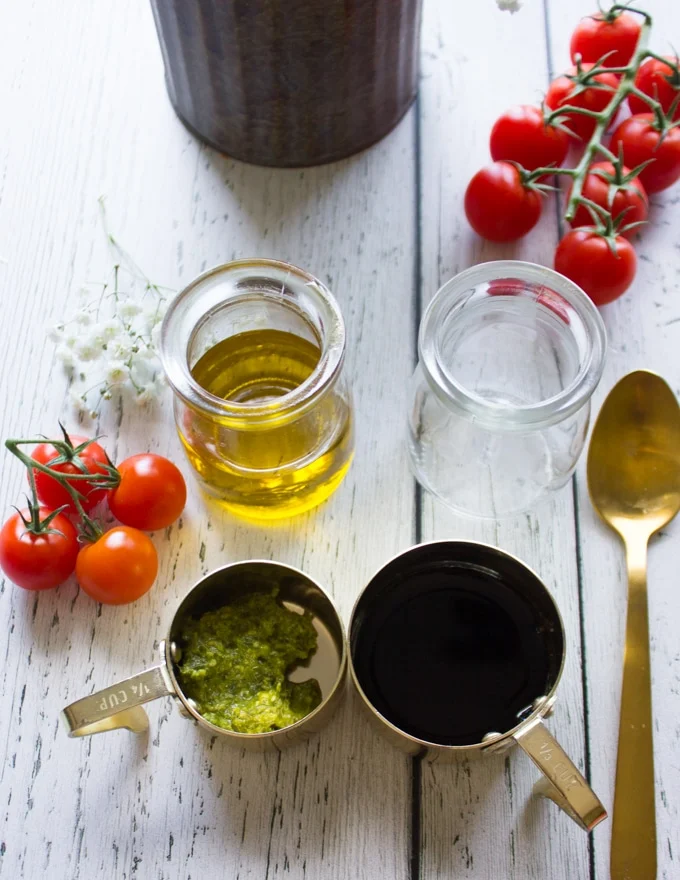ingredients to make the caprese salad dressing including basil pesto, balsamic vinegar and olive oil