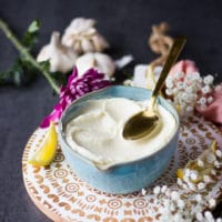 A spoon sliding over a bow of garlic sauce recipe showing the thickness of the sauce