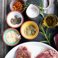 spice blend for NBY strip steak including small bowls of salt, pepper, onion flakes, dried rosemary and olive oil