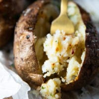 A fork showing the inside of an air fryer baked potato showing the fluffy inside