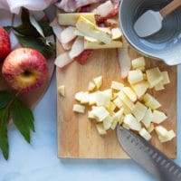 Apples being chopped on a cutting board, peeled and desseded