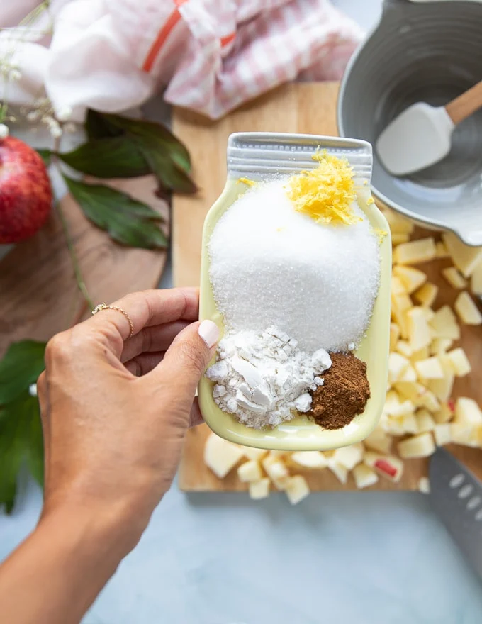 A plate with sugarm flour, cinnamon and lemon zest to be mixed with the diced apples to make apple crumble fillling