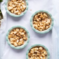 the apple filling is divided between four baking dishes on a baking sheet