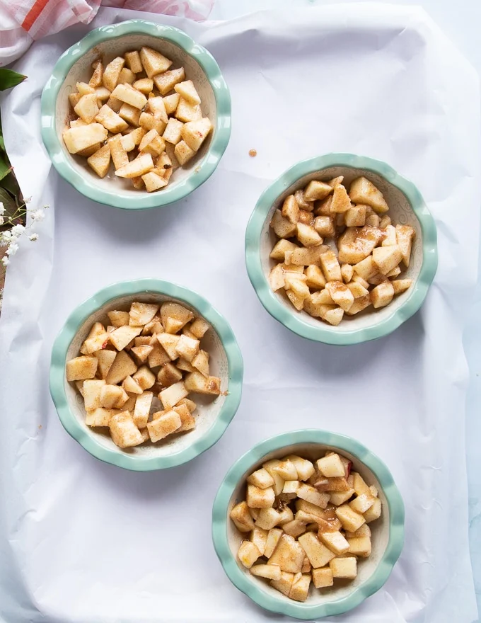 the apple filling is divided between four baking dishes on a baking sheet
