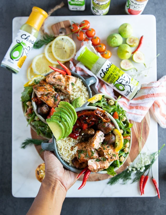 A hand holding a bowl of grilled salmon salad made into a salad bowl for lunch