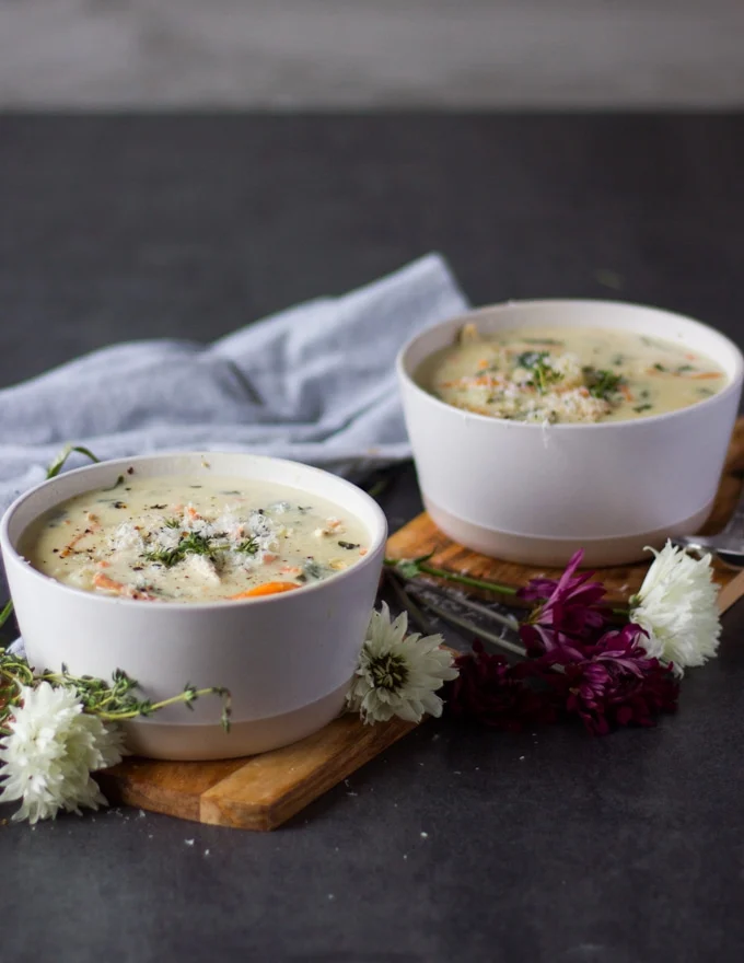 two bowls of gnocchi soup on a wooden board