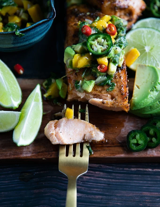 A fork breaking up a piece of salmon cooked in the air fryer showing the succulent texture