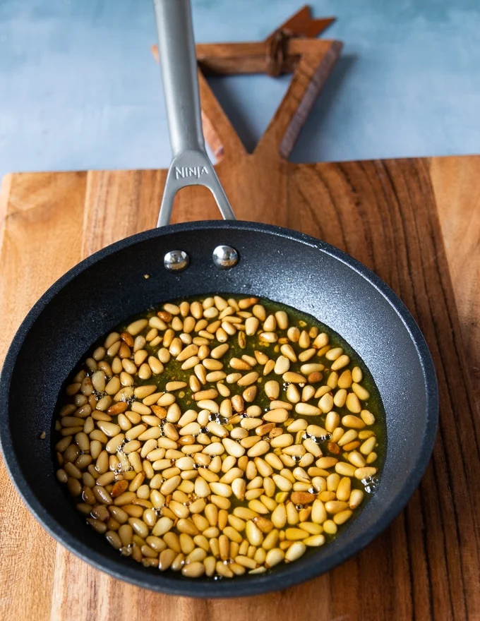 the skillet with the toasted golden pine nuts in olive oil