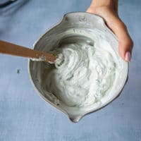 A hand holding a bowl of the finished yogurt sauce