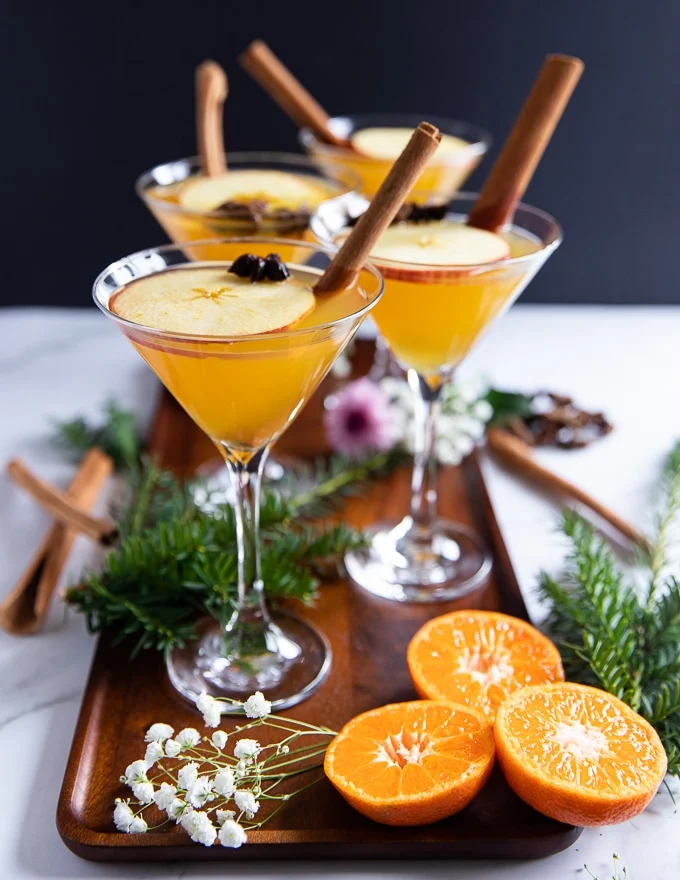 warm appletini mocktail in serving cups garnished with fresh apple slices and cinnamon sicks