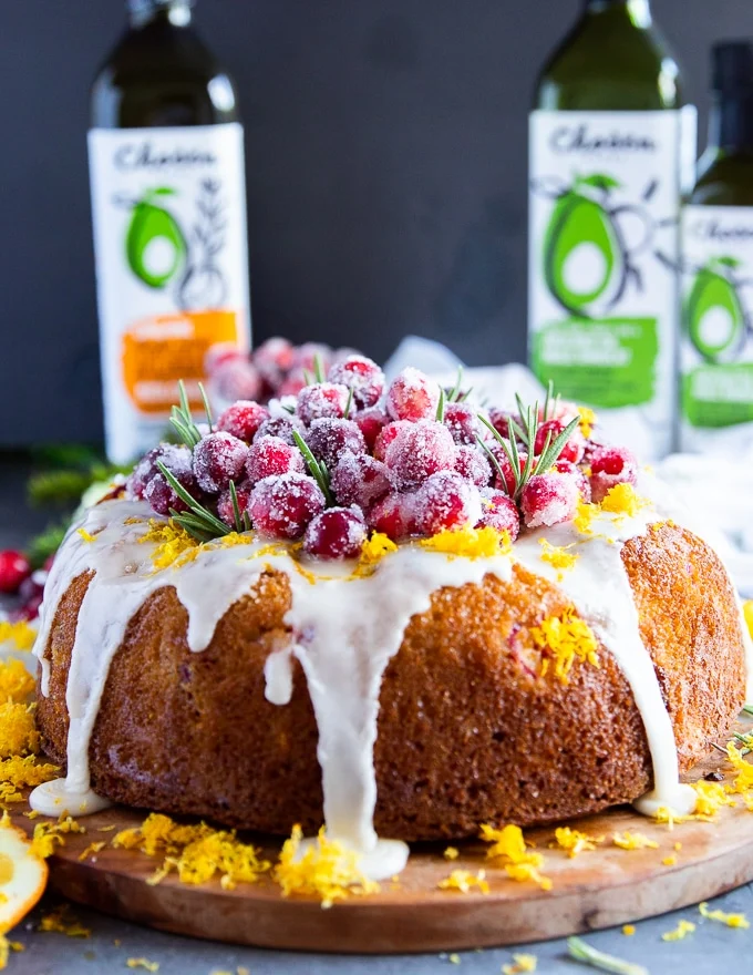 A glazed orange cake over a board with sugared cranberries