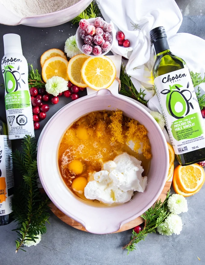 wet ingredients for the orange cake in a larger bowl inclusing eggs, yogurt, oil, zest and juice of orange and sugar